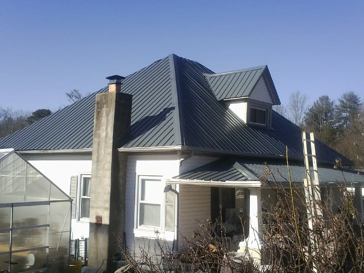 Dark blue standing seam metal roof on a white farmhouse with dormer — Slate & Tile Roof Repair by Roofing Brothers in Grindstone
