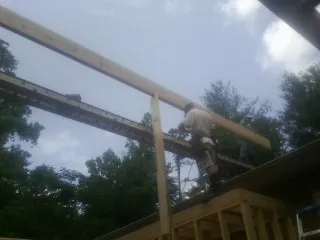 Carpenter setting a ridge beam over a new addition frame — Ice Dam Removal by Roofing Brothers in Grindstone