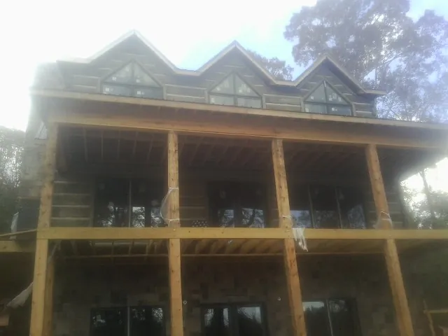 Dormers and porch framing on a large log home under construction — Roof Coating work by our crew in Grindstone