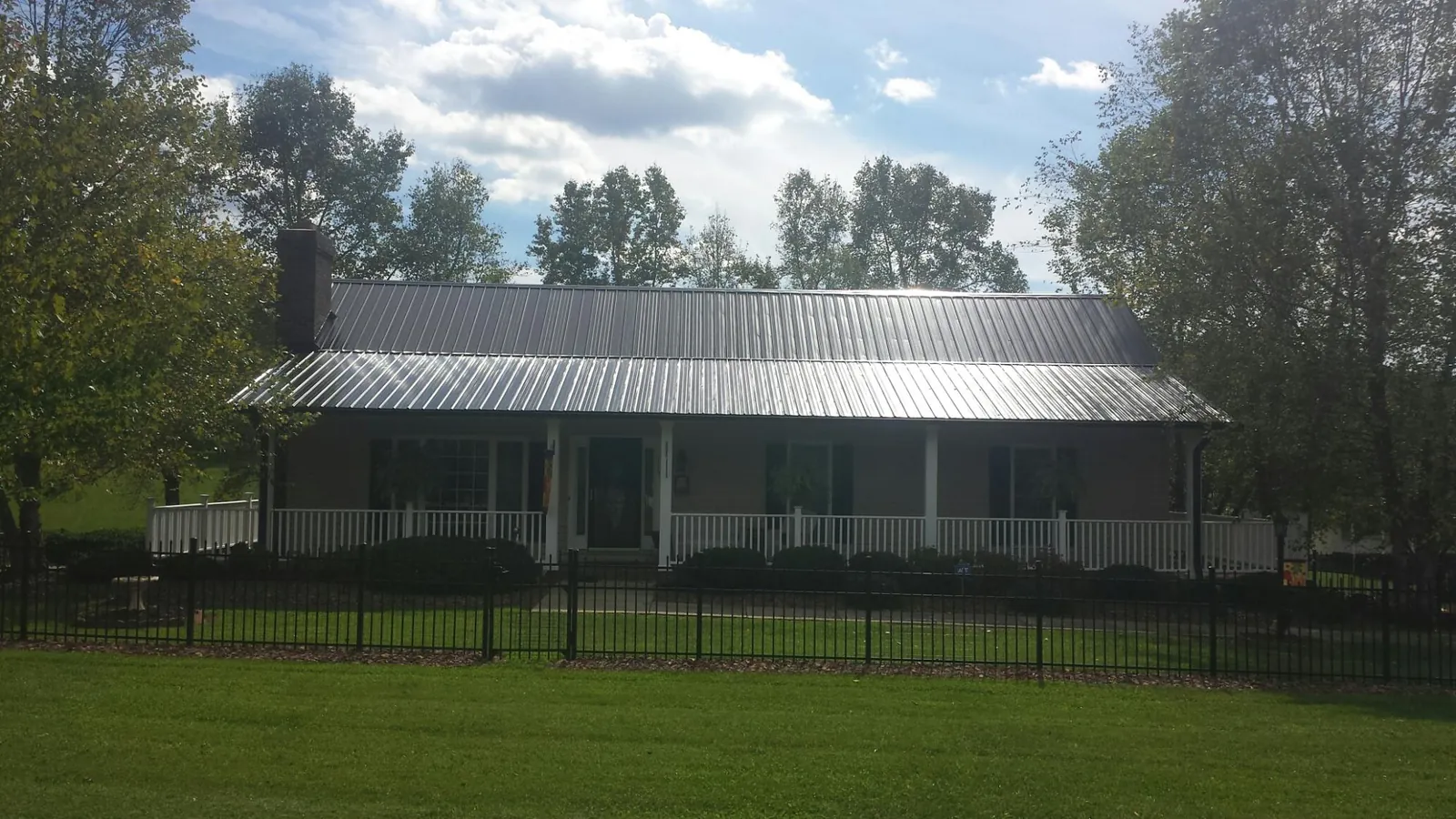 Gray metal roof on a brick ranch with a full width front porch — Gutter Guard Installation work by our crew in Grindstone