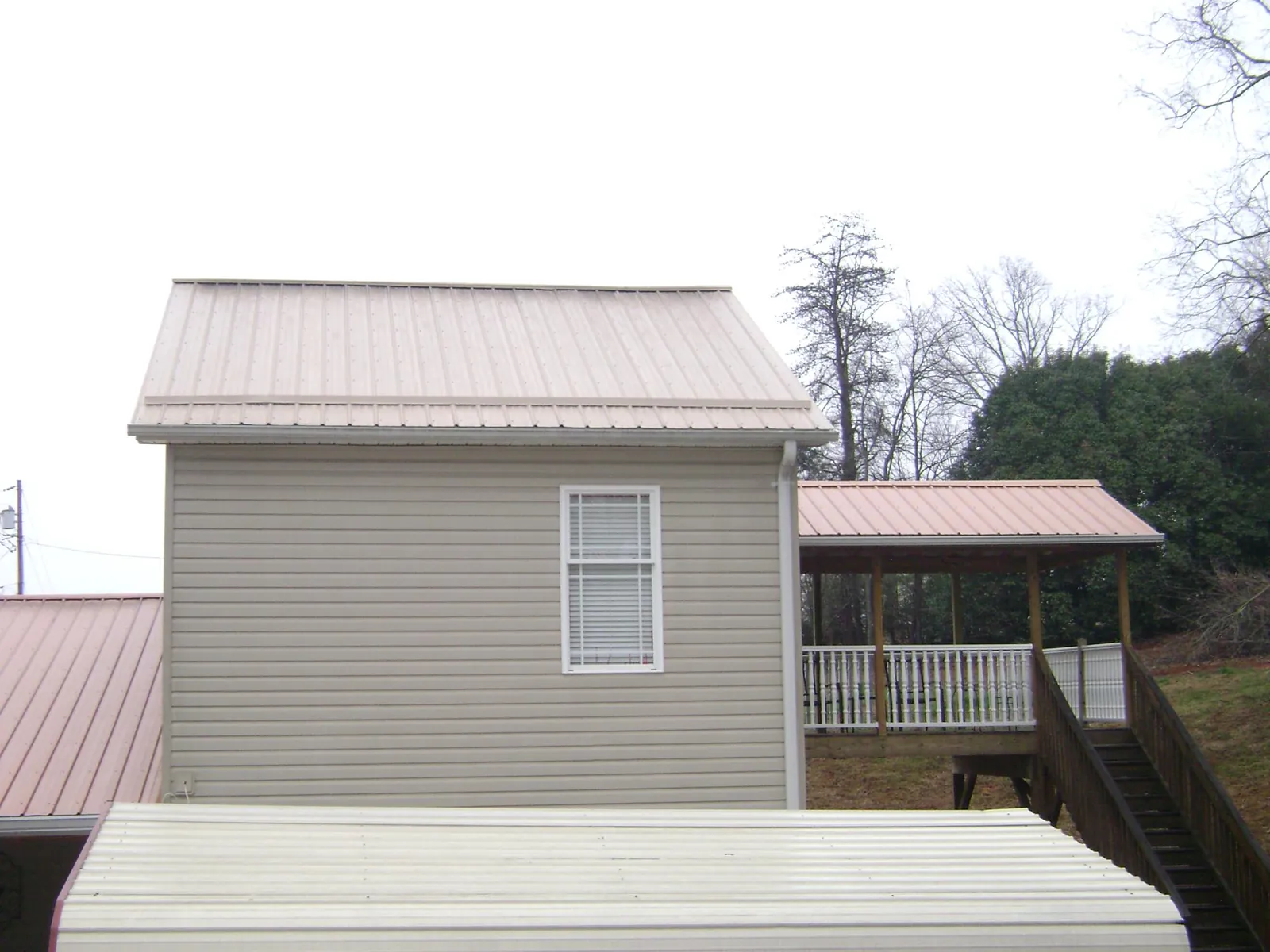 Tan metal roofs on a two story addition and attached porch, from a Roof Replacement job in Grindstone