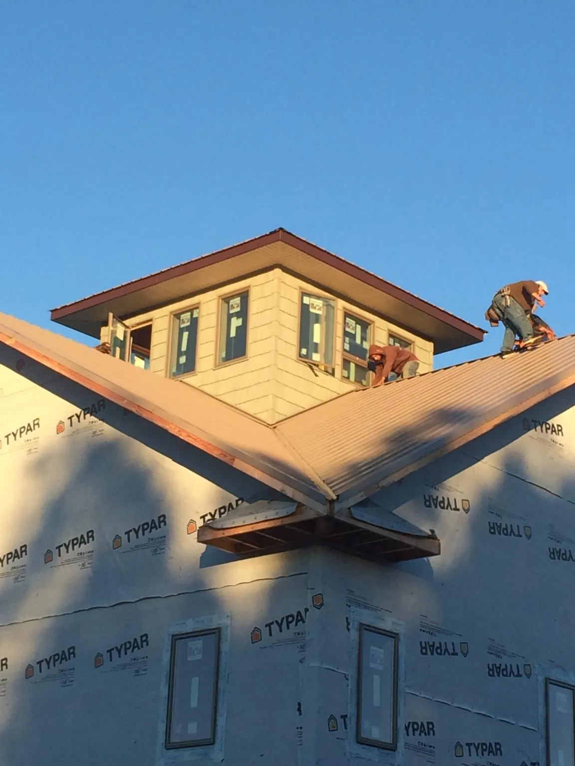 Roofers working around a rooftop cupola on a new metal roof at sunset — Roof Waterproofing in Grindstone by Roofing Brothers
